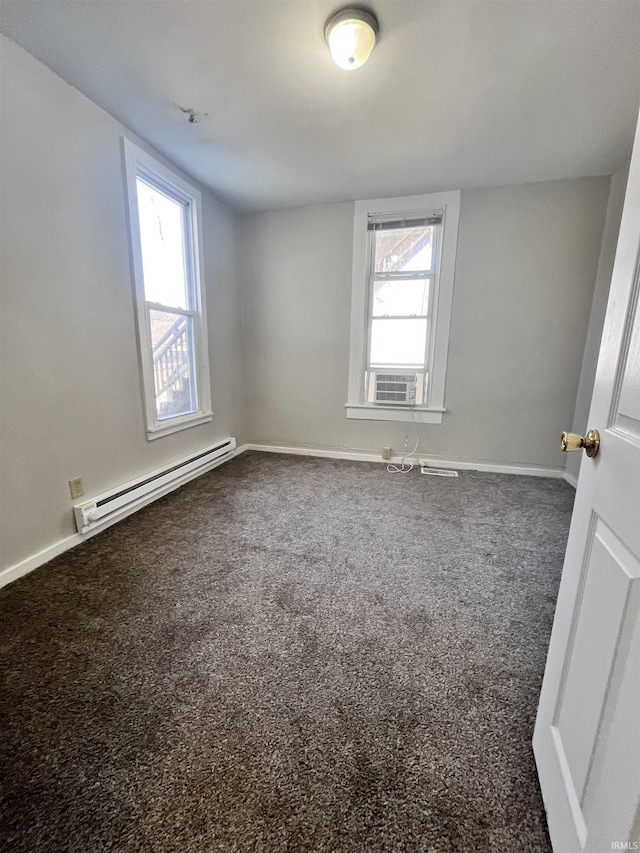 carpeted spare room featuring a baseboard heating unit, baseboards, a healthy amount of sunlight, and cooling unit