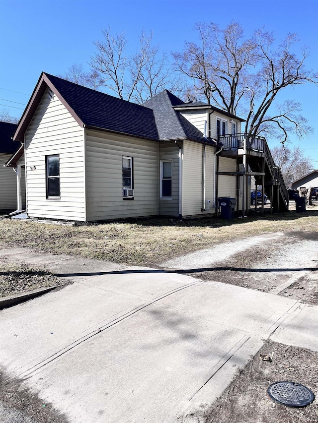 view of side of property with stairway and roof with shingles