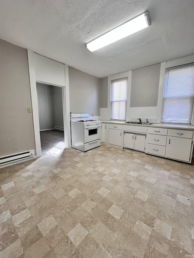 kitchen featuring light countertops, white range with gas cooktop, baseboard heating, white cabinets, and a sink