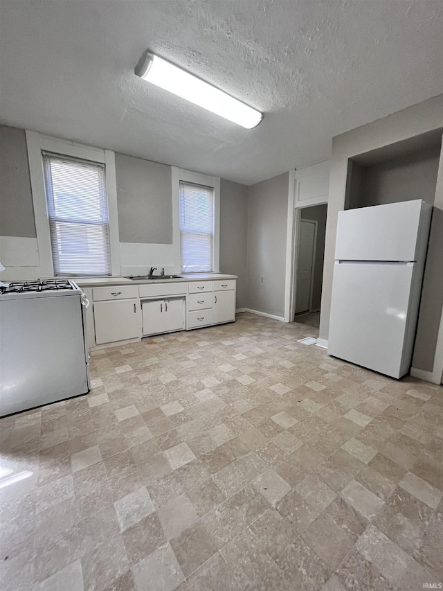 kitchen featuring plenty of natural light, range with gas cooktop, freestanding refrigerator, and a sink