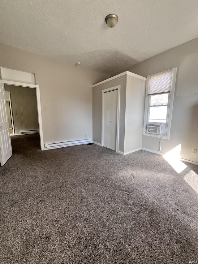 unfurnished bedroom with a baseboard heating unit, carpet floors, a textured ceiling, and baseboards