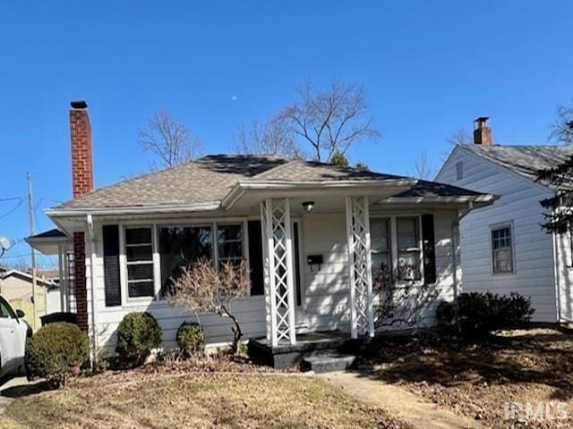 bungalow-style home featuring covered porch and a chimney