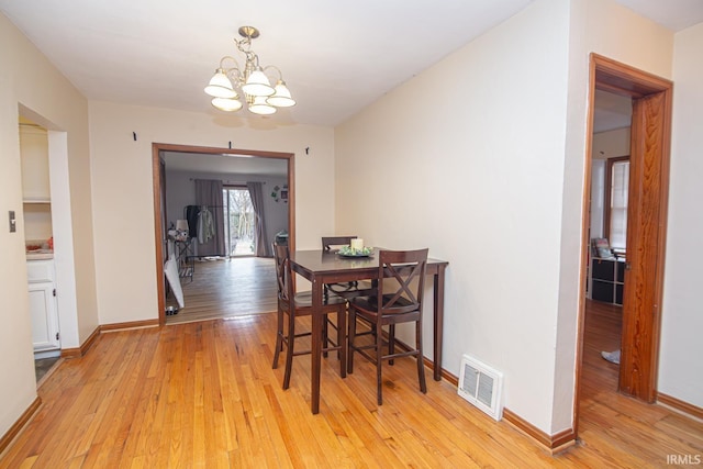 dining room with light wood-style flooring, baseboards, visible vents, and a chandelier