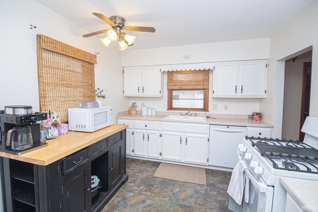 kitchen with white appliances, white cabinetry, dark cabinetry, and a sink