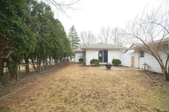 back of property with fence, a lawn, and an outdoor fire pit