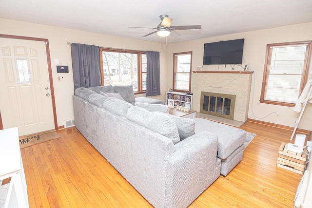 living area with visible vents, baseboards, hardwood / wood-style floors, and a fireplace