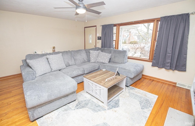 living area featuring visible vents, a ceiling fan, baseboards, and hardwood / wood-style floors