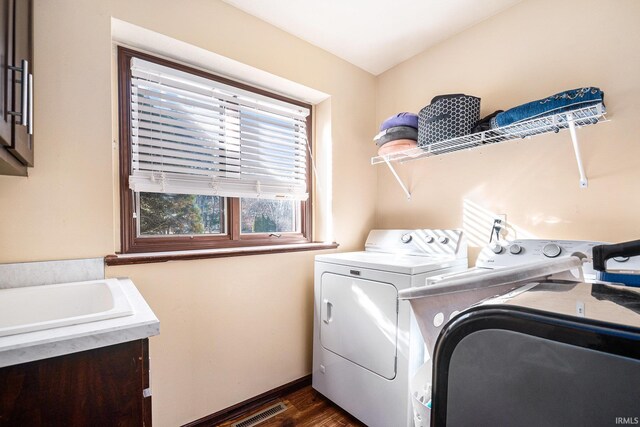 clothes washing area featuring visible vents, cabinet space, dark wood-style floors, and washing machine and clothes dryer