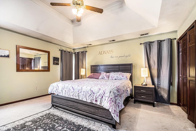 bedroom featuring a tray ceiling, visible vents, light carpet, and baseboards