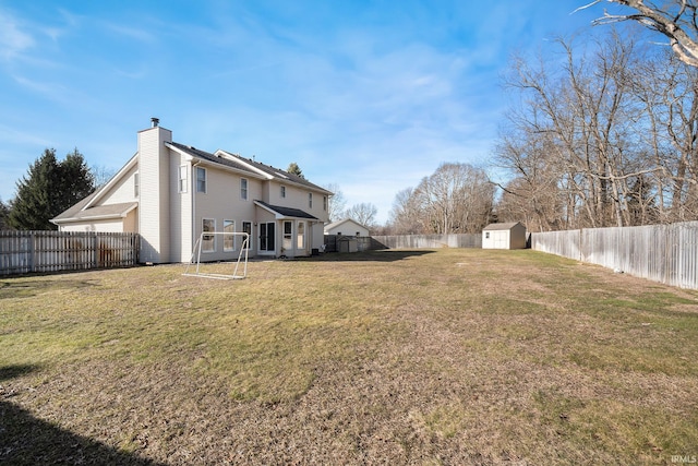 view of yard with a storage shed, a fenced backyard, and an outbuilding