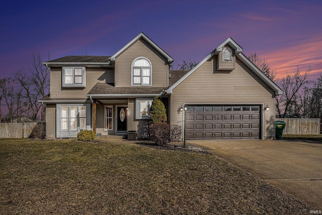 traditional-style home featuring a yard, driveway, an attached garage, and fence