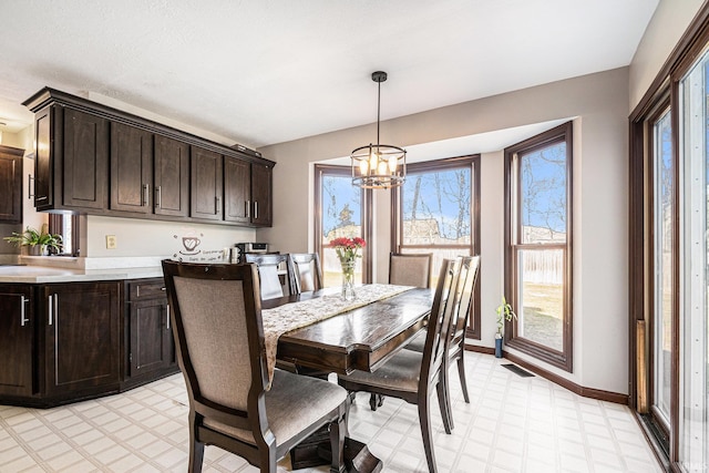 dining room with an inviting chandelier, light floors, visible vents, and baseboards