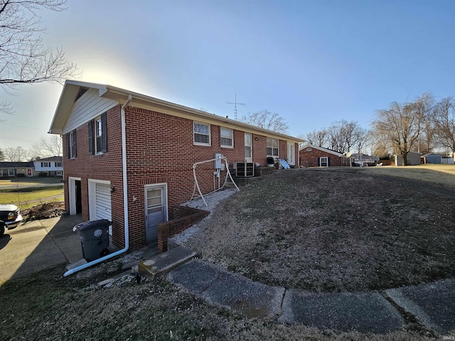 view of property exterior with central AC, an attached garage, brick siding, and driveway