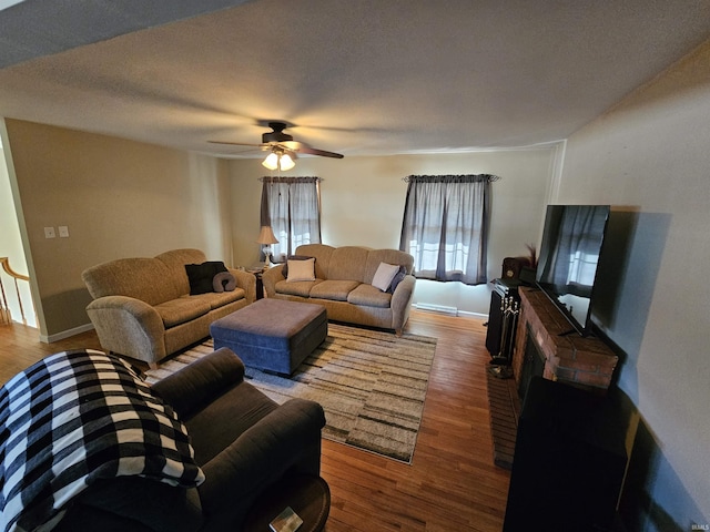 living area with ceiling fan, baseboards, a textured ceiling, and wood finished floors