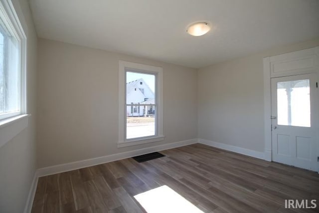 unfurnished room featuring plenty of natural light, baseboards, and dark wood-style flooring