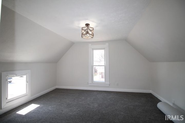 additional living space featuring lofted ceiling, baseboards, and dark carpet