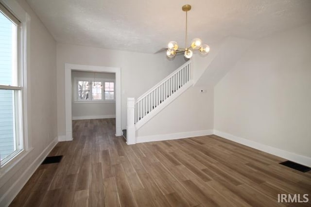 interior space with baseboards, wood finished floors, visible vents, and a chandelier