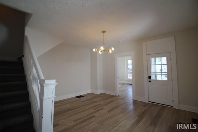 entrance foyer with stairway, visible vents, baseboards, dark wood finished floors, and a notable chandelier