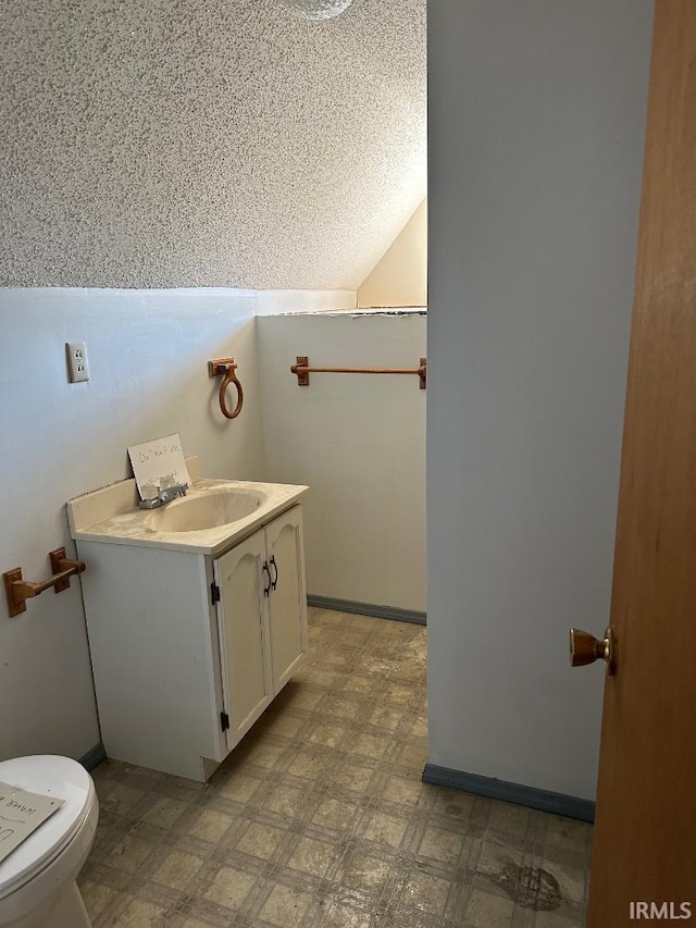 half bath featuring tile patterned floors, toilet, vanity, and lofted ceiling