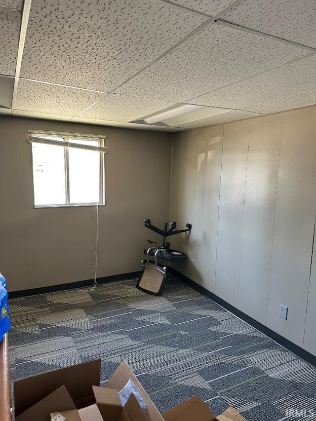 workout room featuring baseboards, a paneled ceiling, and carpet flooring