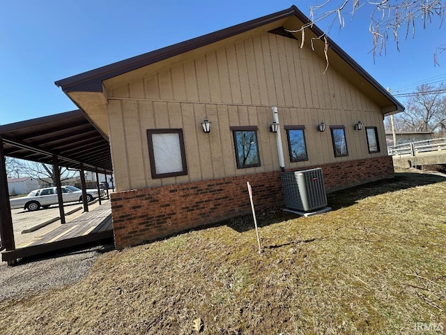 view of side of home with cooling unit, brick siding, and a carport