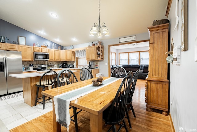 dining space featuring lofted ceiling, recessed lighting, light wood-type flooring, and a chandelier