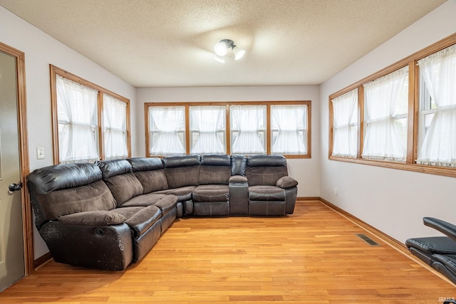 living area featuring visible vents, a textured ceiling, and light wood finished floors