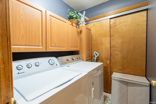 laundry room featuring washer and clothes dryer, cabinet space, and a textured ceiling