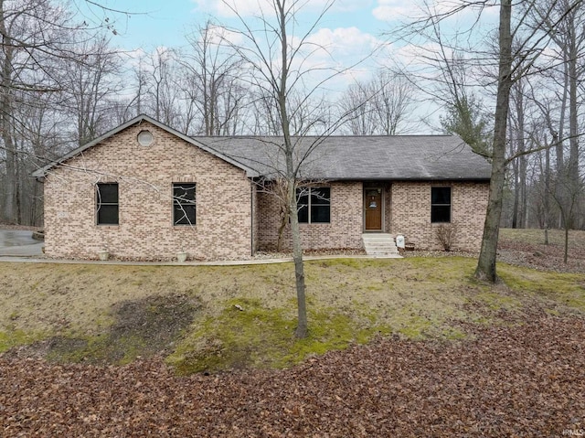 ranch-style home featuring brick siding and roof with shingles