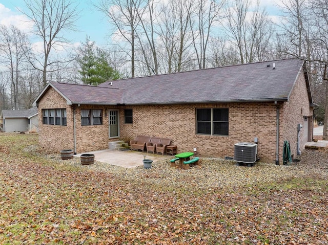 back of property featuring central air condition unit, entry steps, roof with shingles, brick siding, and a patio area