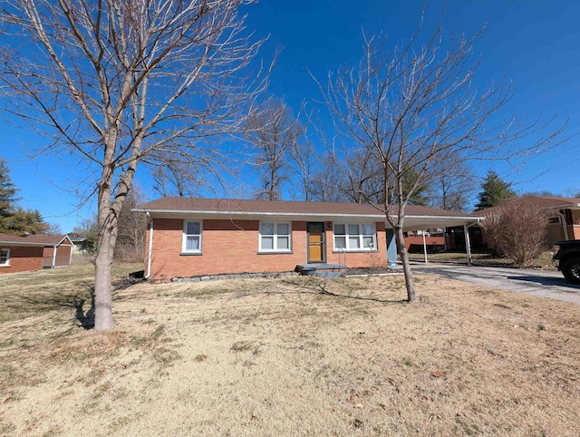 ranch-style home with a carport, a front yard, brick siding, and driveway