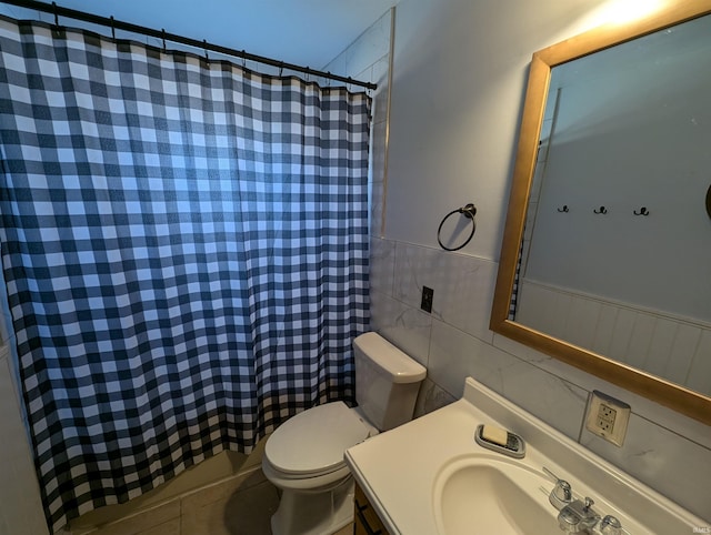 bathroom with toilet, curtained shower, tile walls, wainscoting, and vanity