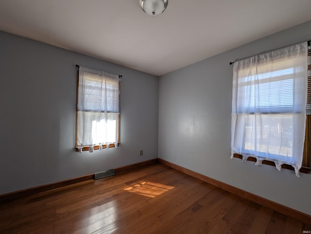 unfurnished room featuring visible vents, a healthy amount of sunlight, and wood finished floors