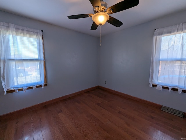 spare room featuring ceiling fan, visible vents, baseboards, and wood finished floors