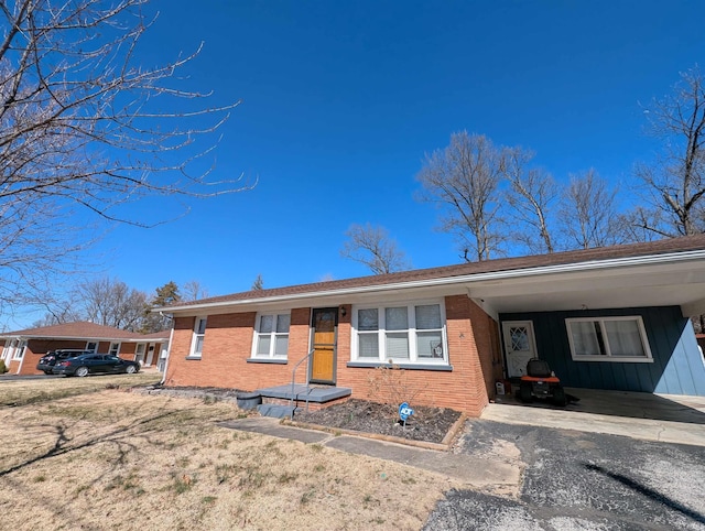 single story home with a carport, brick siding, and driveway