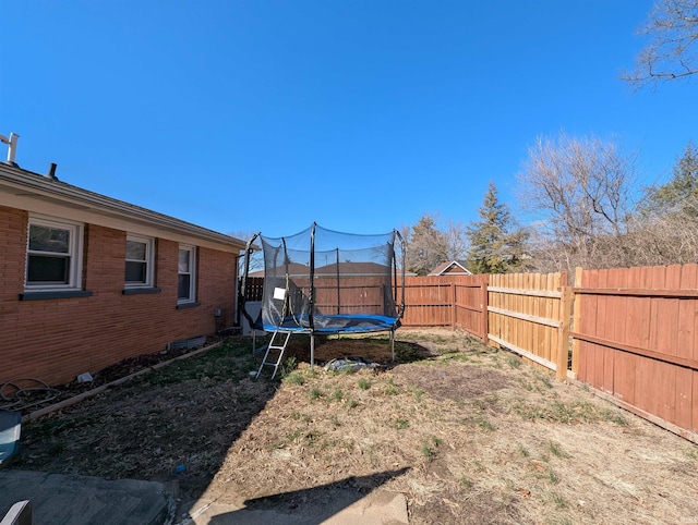 view of yard with a trampoline and a fenced backyard