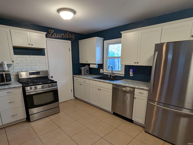 kitchen with a sink, white cabinets, tasteful backsplash, and stainless steel appliances