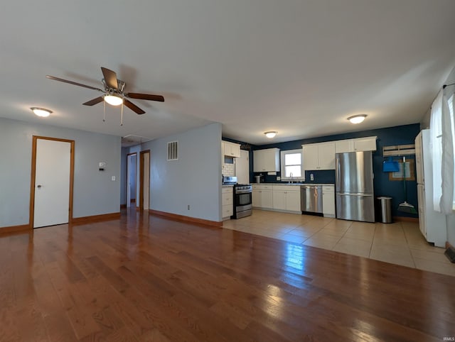 unfurnished living room with a sink, visible vents, baseboards, and light wood finished floors