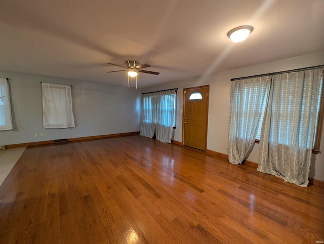 unfurnished living room featuring ceiling fan, visible vents, baseboards, and wood finished floors