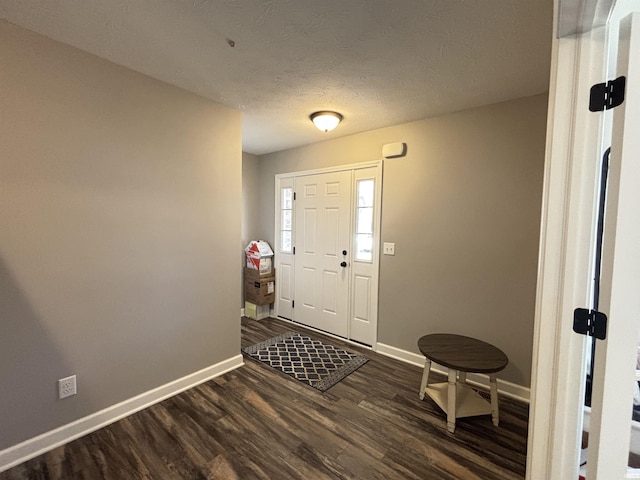 foyer entrance featuring baseboards, a textured ceiling, and dark wood-style flooring