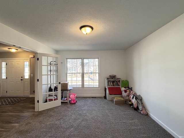 rec room featuring baseboards, a textured ceiling, and carpet