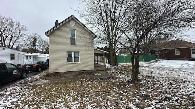 snow covered property featuring fence and a chimney