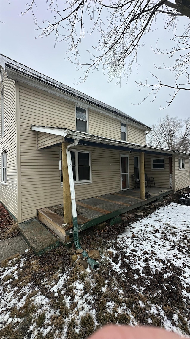 snow covered back of property featuring a wooden deck