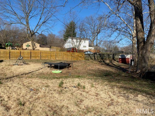 view of yard with an outbuilding, a shed, and fence