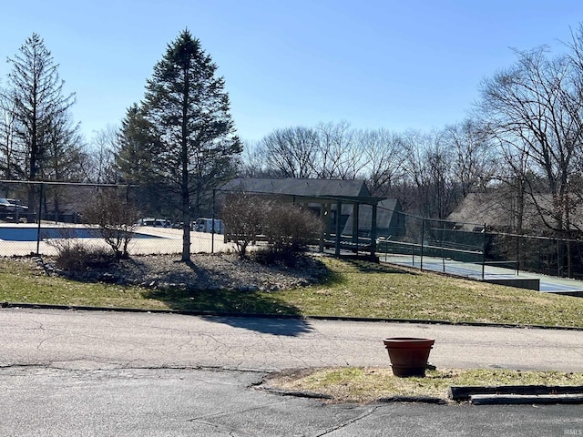 exterior space with a tennis court and fence