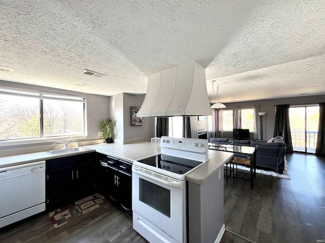 kitchen with white appliances, extractor fan, dark wood-style flooring, and a peninsula