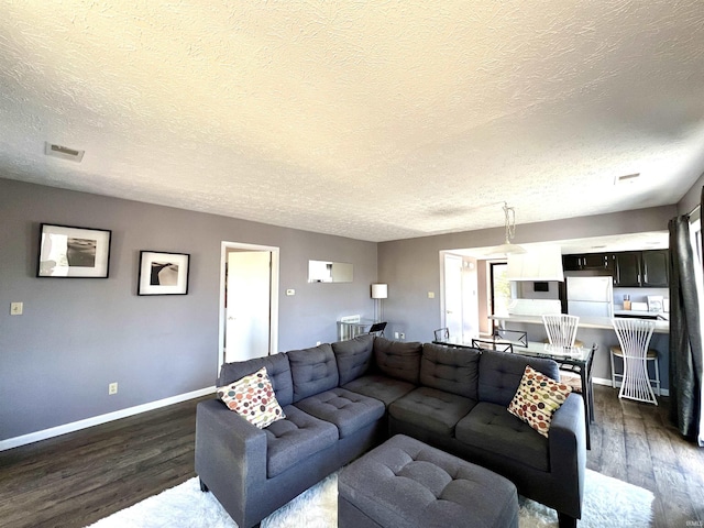 living room with visible vents, baseboards, dark wood-type flooring, and a textured ceiling