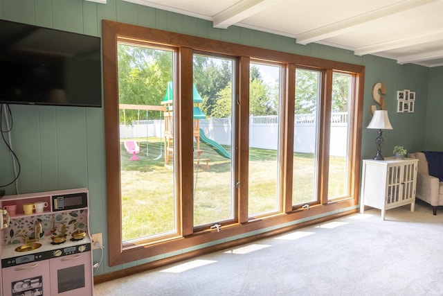 doorway with beamed ceiling, a healthy amount of sunlight, and carpet floors