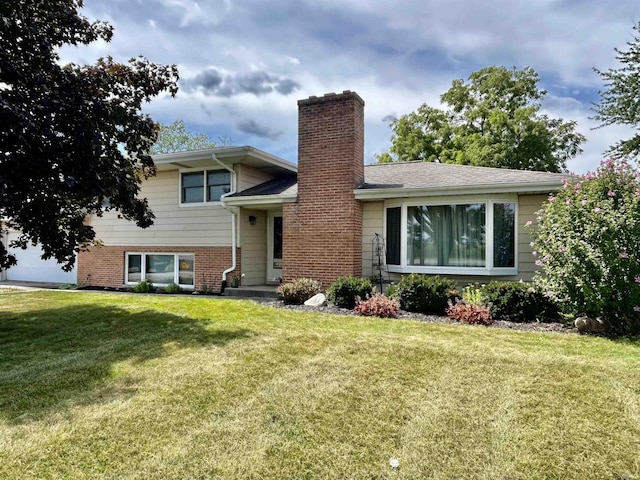 tri-level home with brick siding, a chimney, a front lawn, and a shingled roof