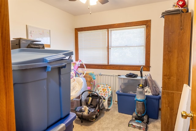 interior space featuring a ceiling fan, radiator heating unit, and carpet